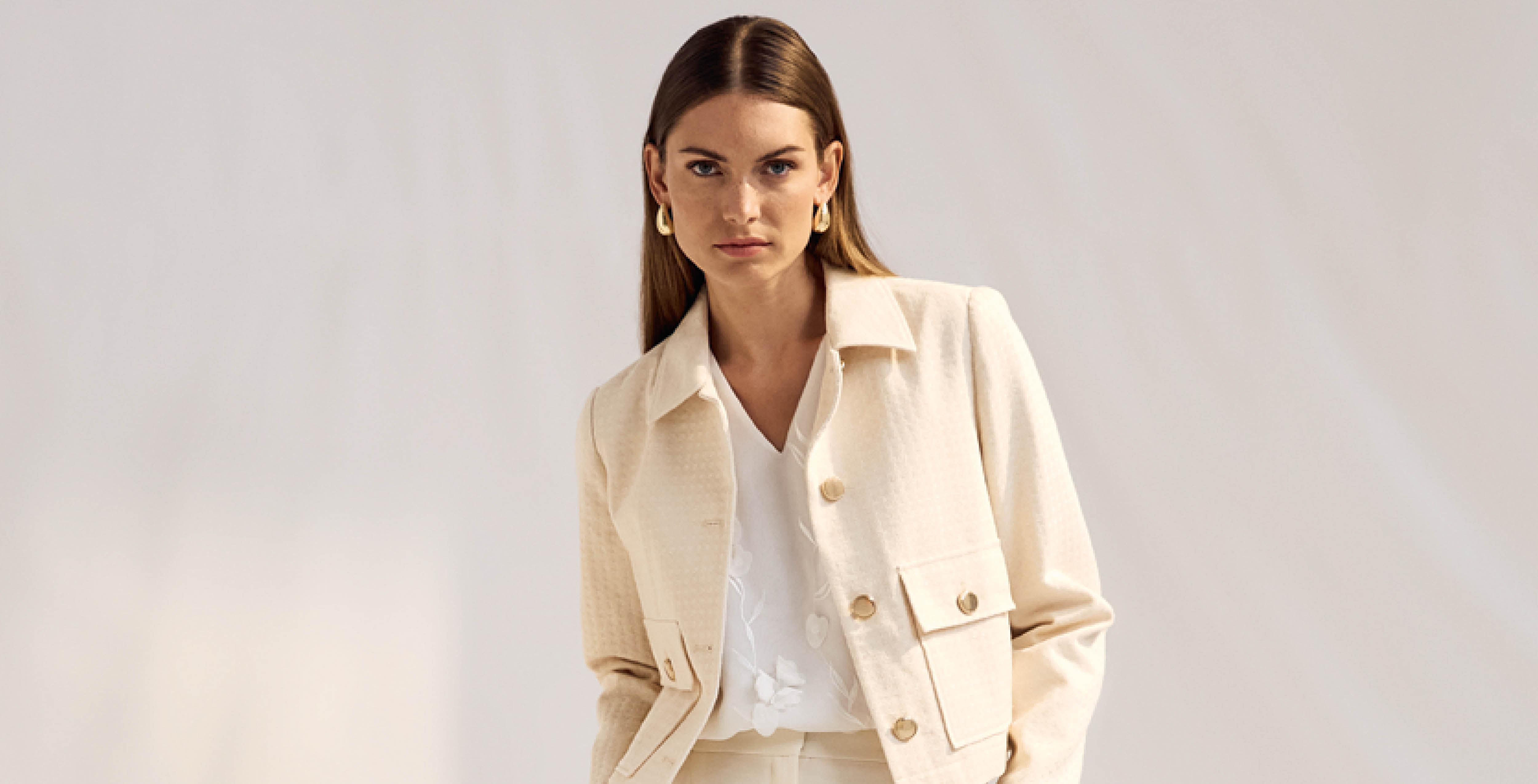 Frau im cremefarbenen Blazer und weißem Oberteil – elegantes Outfit von s.Oliver Black Label Women.