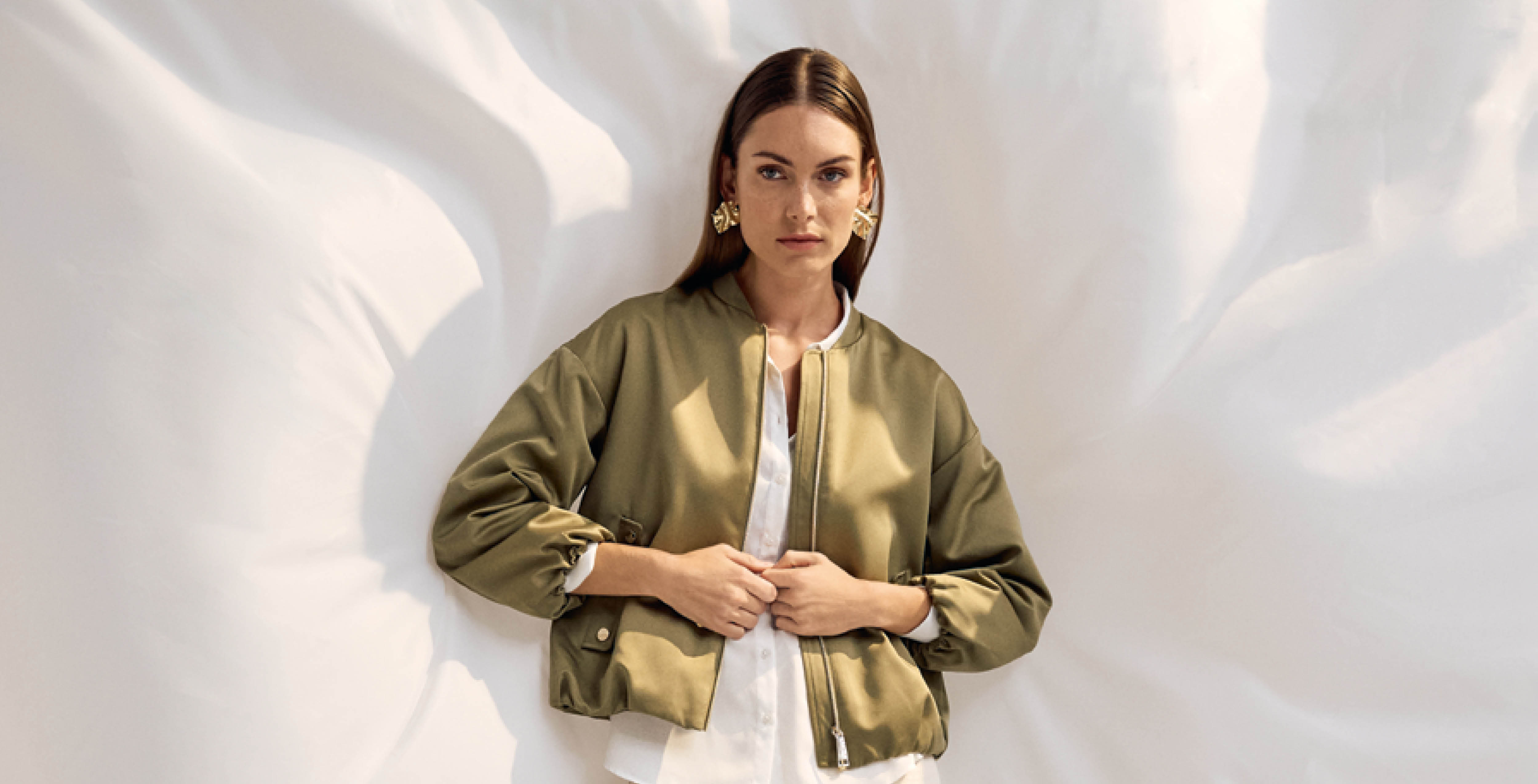 Frau trägt olivgrüne Bomberjacke mit weißen Bluse – stilvoller, moderner Look von s.Oliver Black Label Women
