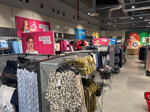 Modische Damenkleidung im Tchibo Prozente Store mit Pop-Art-Schildern