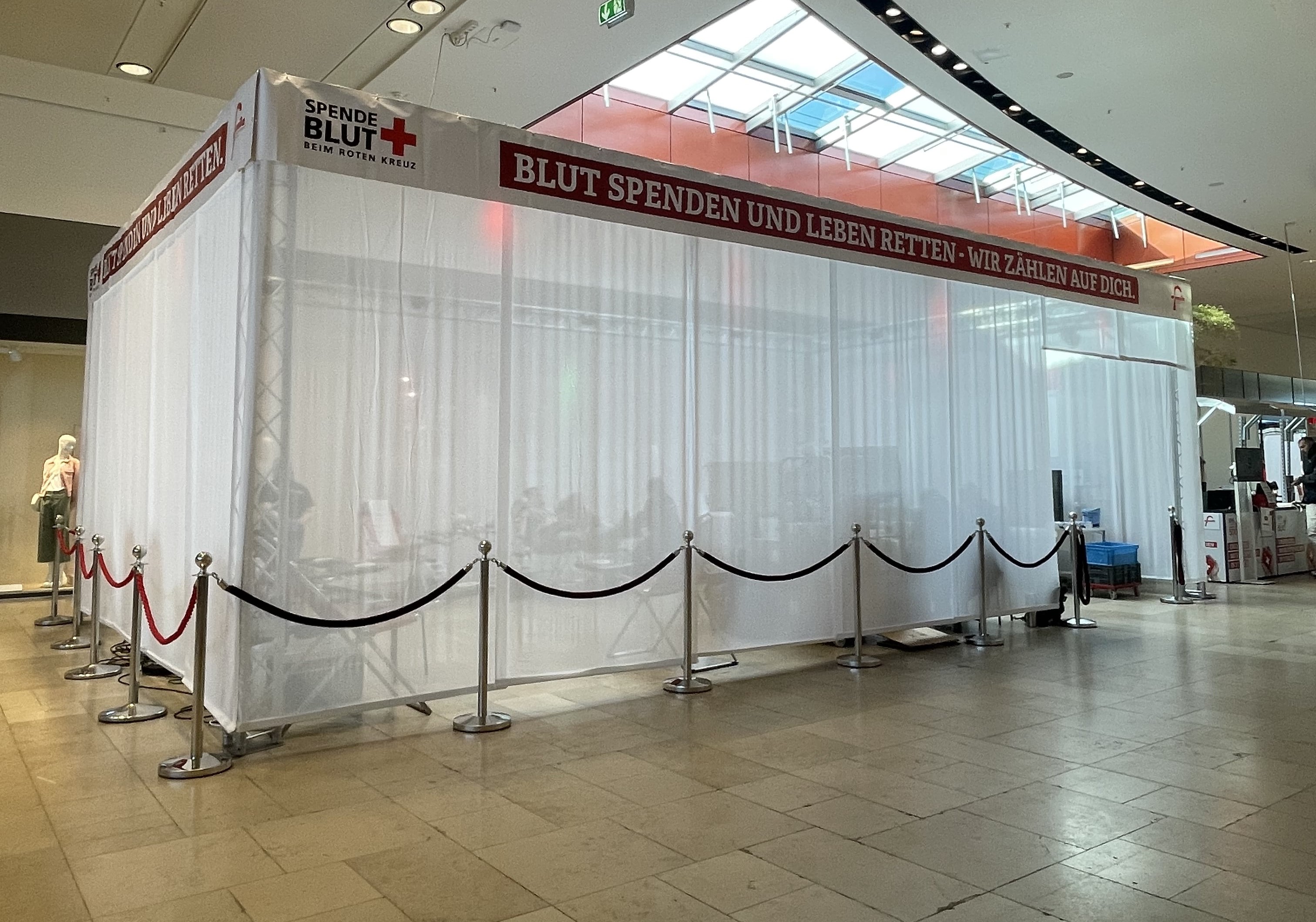 Mehrere Blutspendebänke sind hinter einem weißen Fadenvorhang zu sehen.