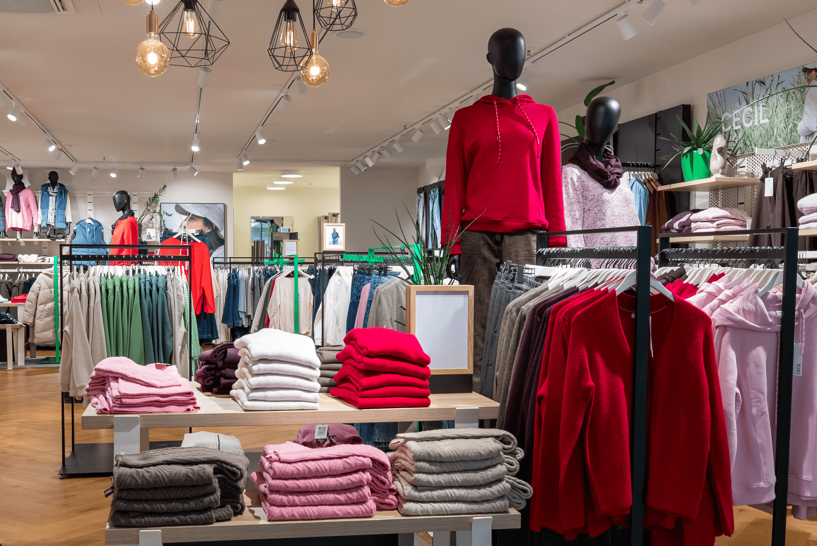 Innenansicht des Cecil Shops mit einem Verkaufstresen mit verschiedenen gestapelten Pullovern in braun und rosa.