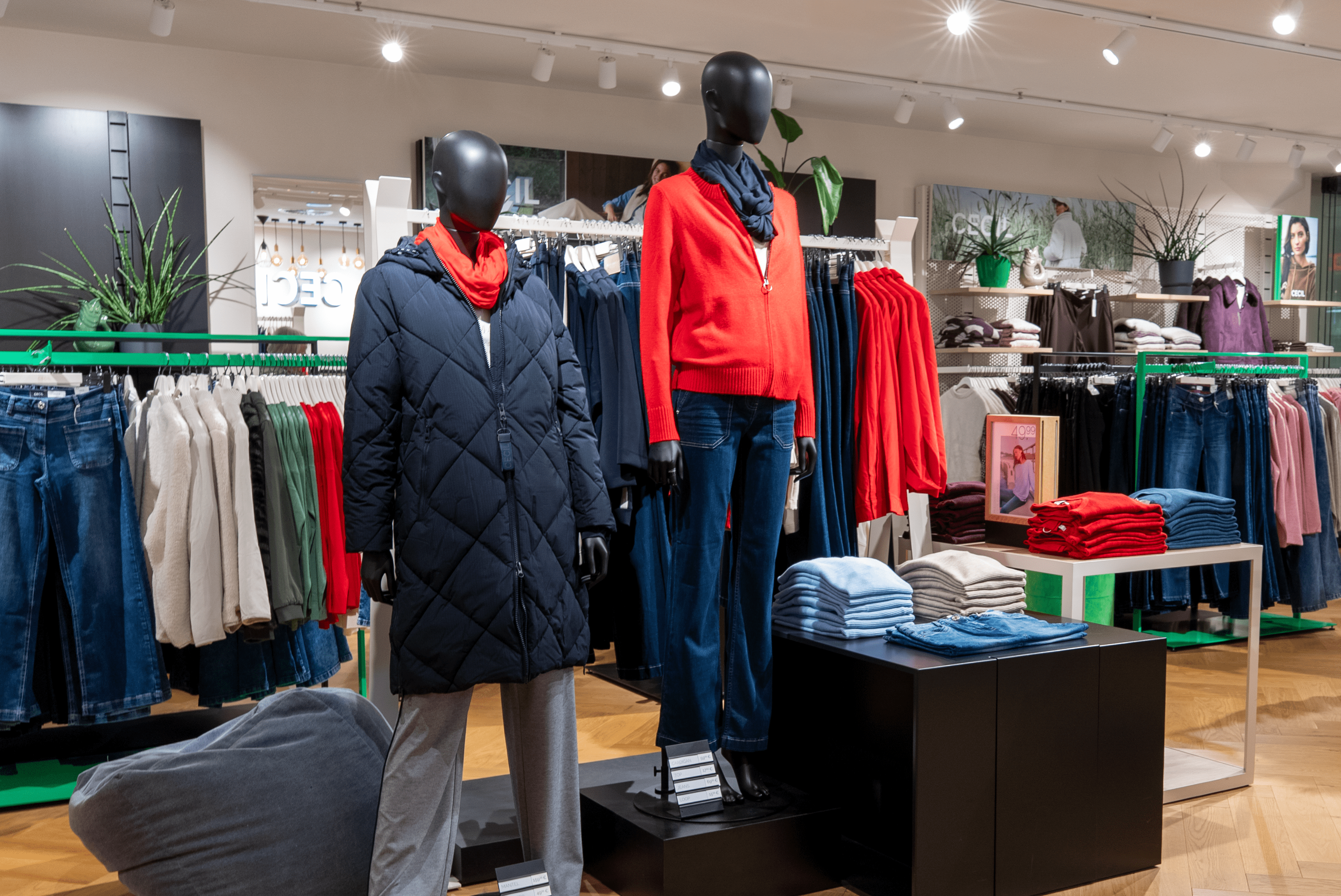 Innenansicht vom Cecil-Store mit zwei Kleiderpuppen im Vordergrund, die eine blaue Steppjacke und eine rote Strickjacke tragen.