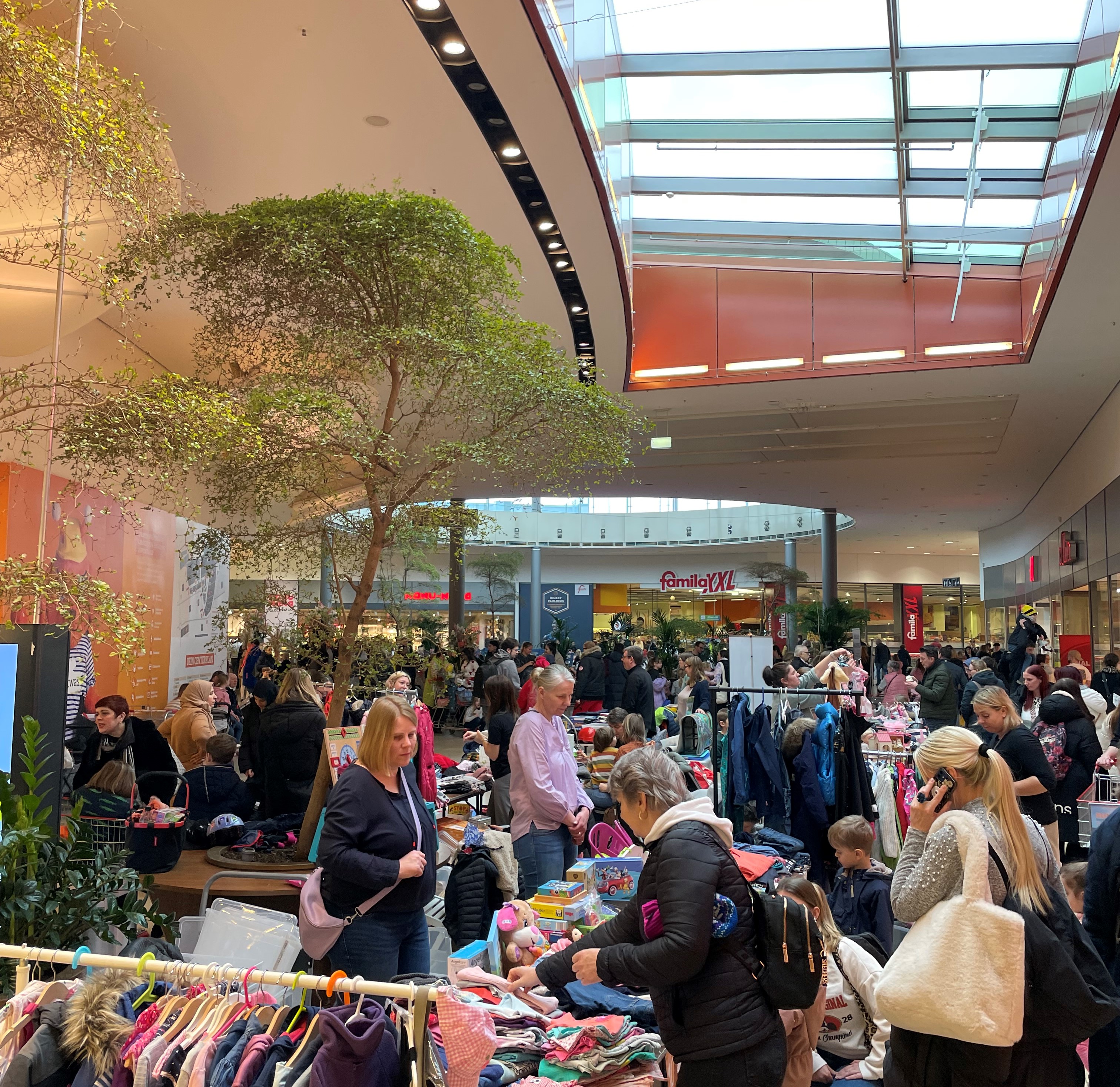 In der Mall stehen Verkaufsstände vom Flohmarkt und Kunden sind beim Kaufen zu sehen.