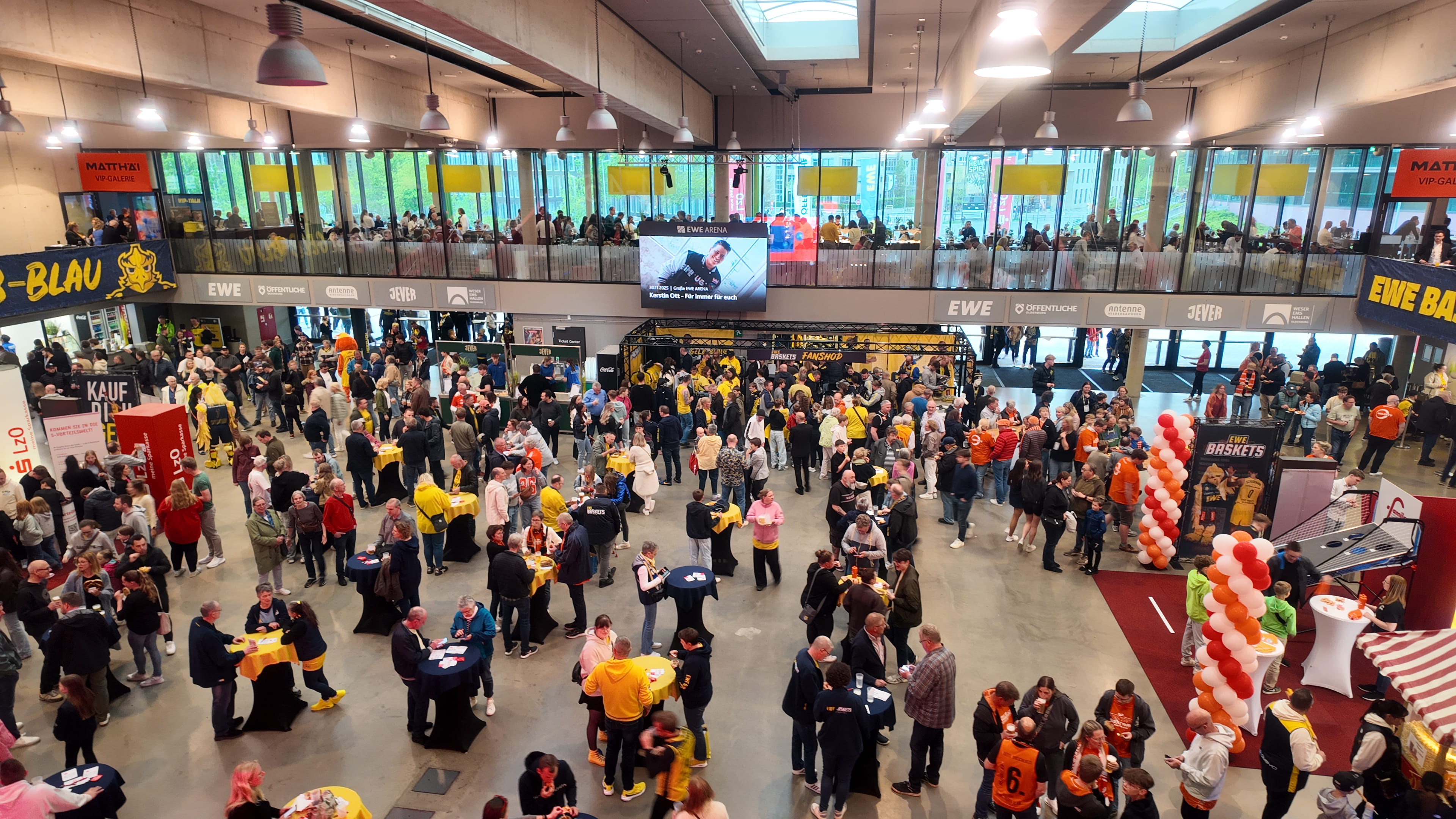 Das Foyer der großen EWE Arena ist voller Baskets Fans, die das Wurfspiel am famila Einkaufsland Stand spielen.