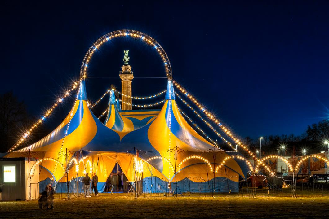 Ein beleuchtetes Zirkuszelt im dunkeln.