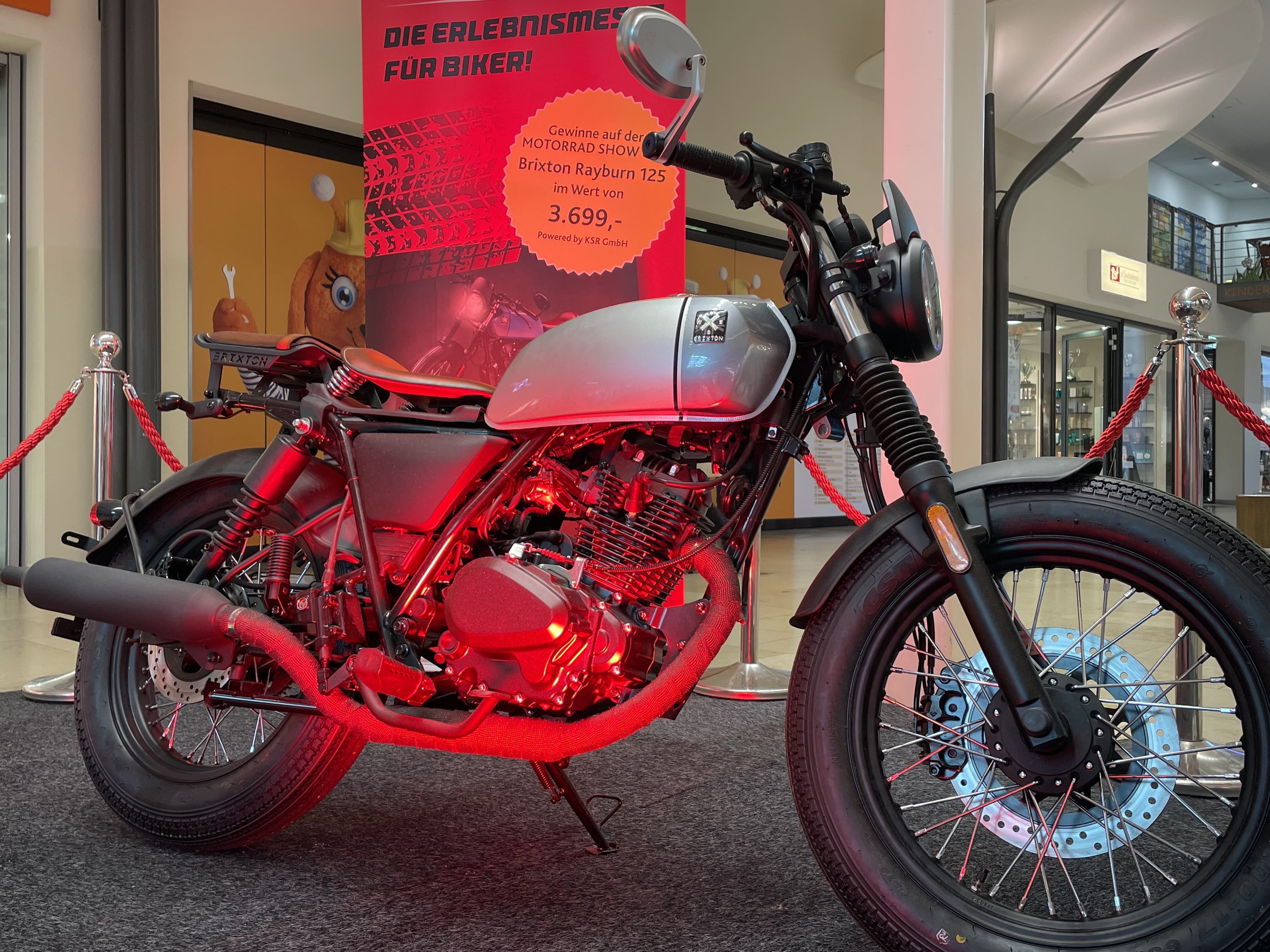 Ein Motorrad wird von roten Lichtern angestrahlt, weil es als Ausstellungsstück in der Mall dient.