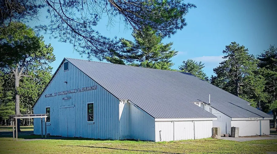 A blue barn with a metal roof in the middle of a field.