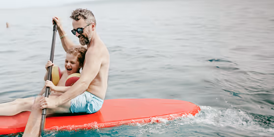 Smiling man kayaking with his child, symbolizing the vitality, wellness, and active lifestyle supported by Gameday Men’s Health vitamin injection therapies.