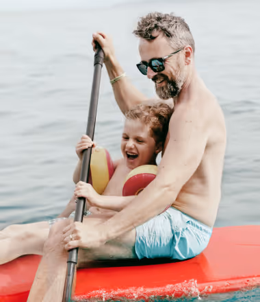 Smiling man kayaking with his child, symbolizing the vitality, wellness, and active lifestyle supported by Gameday Men’s Health vitamin injection therapies.