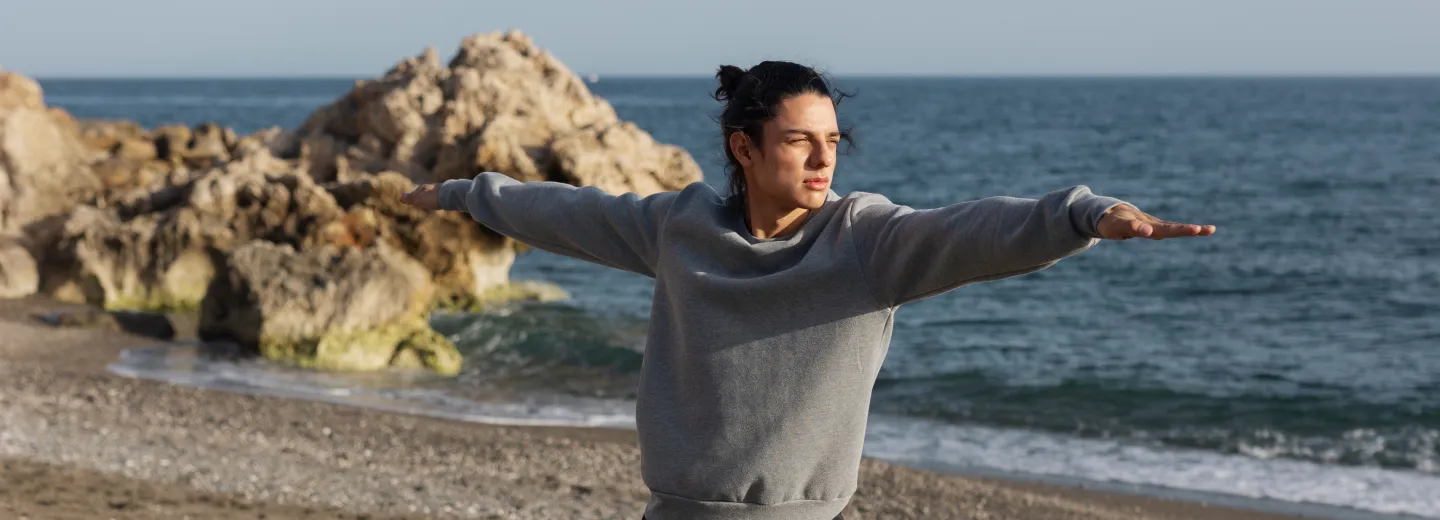 Man practicing yoga on the beach at sunrise, representing balance, mindfulness, and overall wellness.