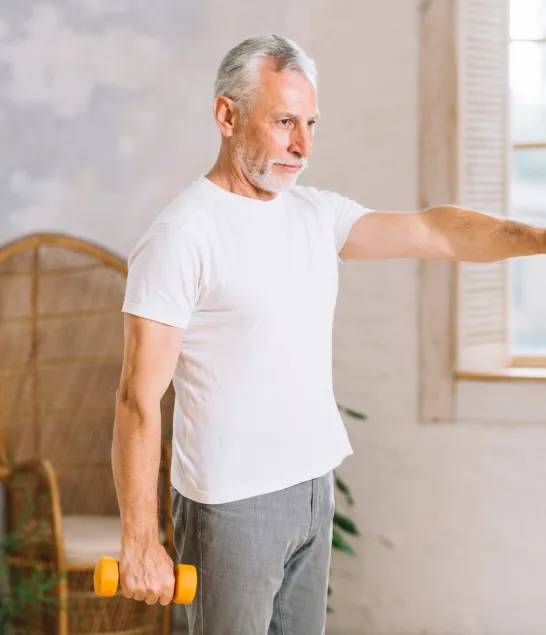Senior man lifting a dumbbell indoors, representing improved muscle function, mood, and energy support from Vitamin B Complex injections for men.