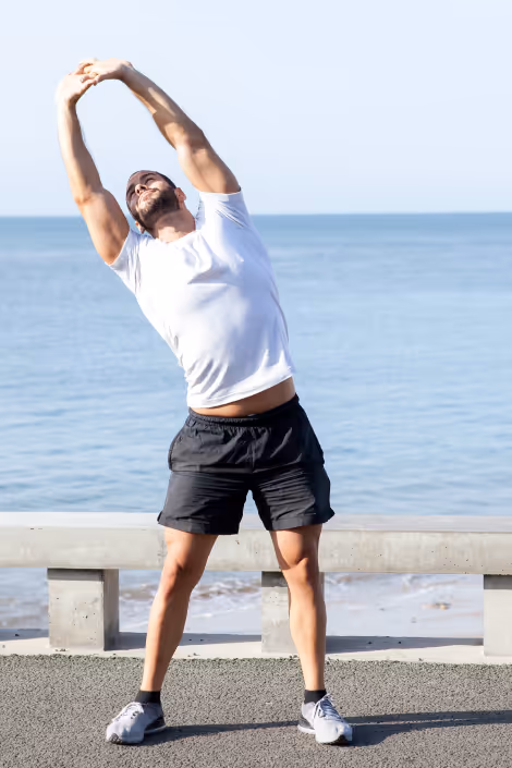 Man stretching by the beach, improving flexibility and recovery with EPAT shockwave therapy for sports injuries