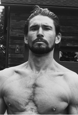 Black and white image of fitness expert Ben Greenfield standing shirtless outdoors, featured as a Gameday Men's Health influencer.