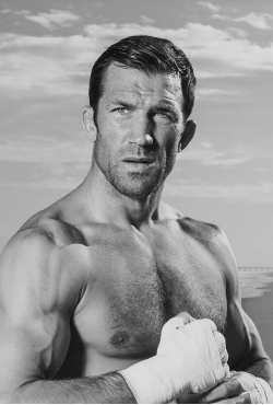 Black and white image of professional MMA fighter Luke Rockhold shirtless with hands wrapped, looking focused, featured as a Gameday Men's Health influencer.
