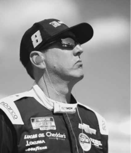 Black and white image of professional race car driver Kyle Busch wearing sunglasses and a racing suit, featured as a Gameday Men's Health influencer.