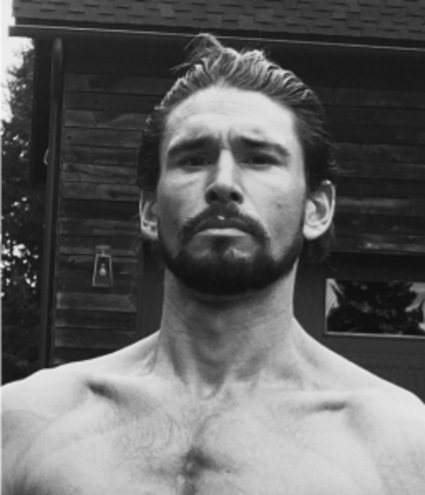 Black and white image of fitness expert Ben Greenfield standing shirtless outdoors, featured as a Gameday Men's Health influencer.