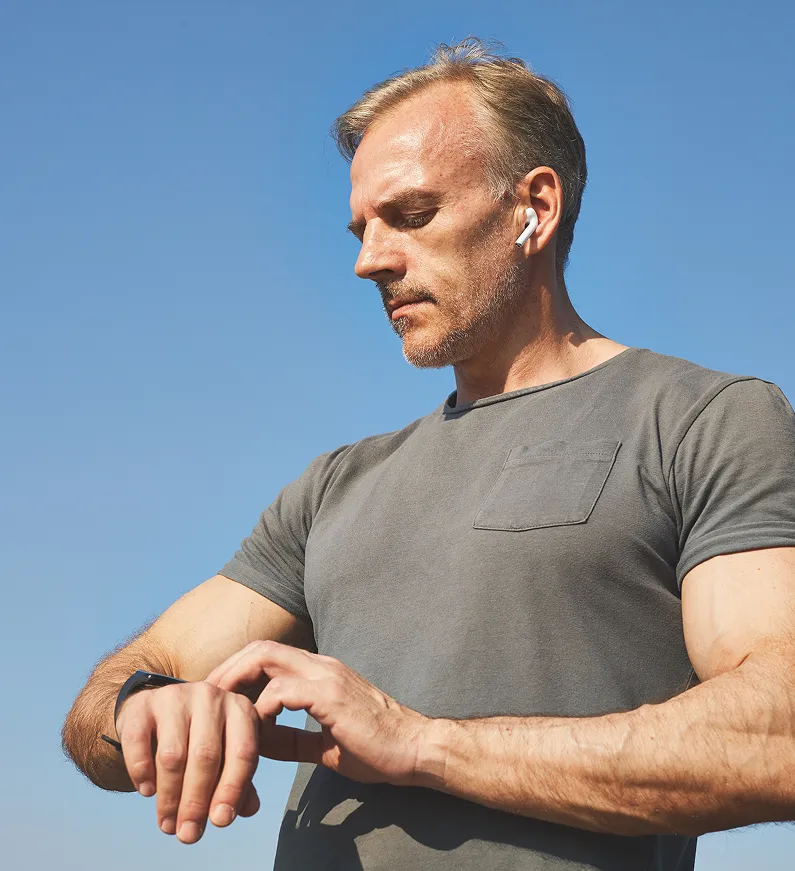 Man checking his smartwatch outdoors after a vitamin injection session