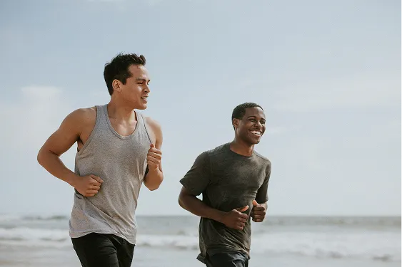 Two men jogging outdoors and smiling, representing increased energy and active lifestyle supported by Erectile Dysfunction treatment.