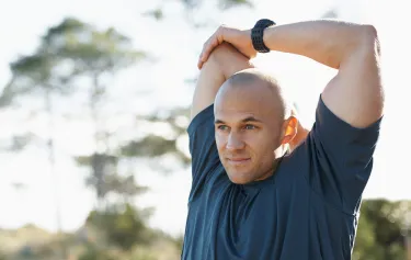 Man stretching outdoors with a focused expression, representing improved physical performance and vitality through GAINSWave® therapy.