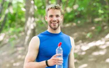 Man running near water with earphones in, reflecting boosted stamina and metabolism support from B vitamin therapy.