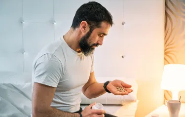 Man examining oral testosterone pills, highlighting convenient at-home treatment option.