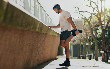 Man stretching leg outdoors before exercise after vitamin injection therapy