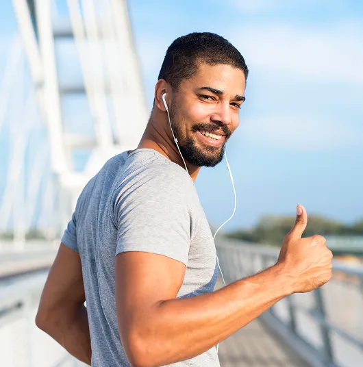  Smiling man giving a thumbs up while exercising outdoors, representing confidence, weight management, and energy from MIC lipotropic injections.