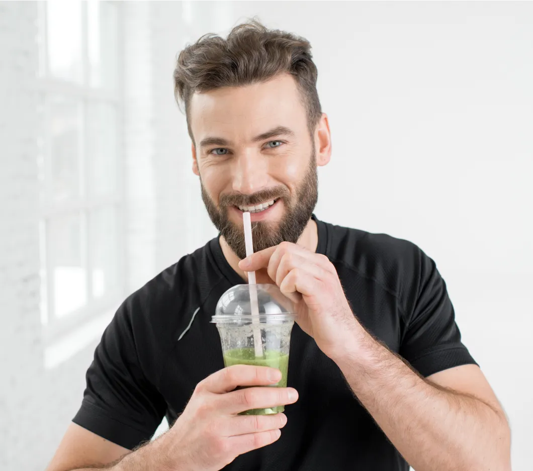 Man enjoying a green smoothie, supporting his weight loss journey with healthy lifestyle choices and medical weight loss solutions