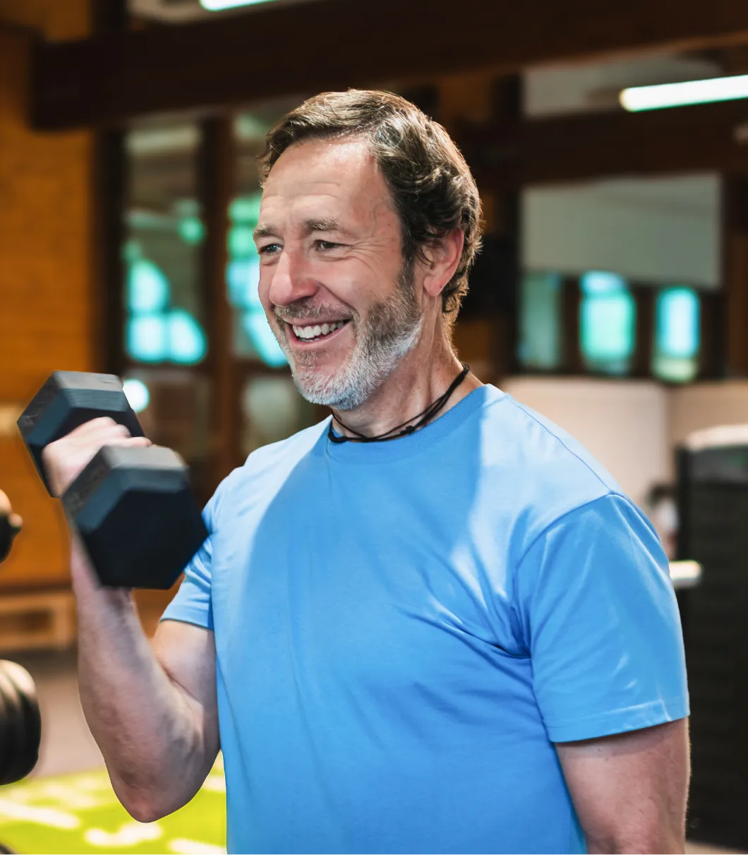 Middle-aged man lifting weights indoors, showcasing strength and energy benefits of Sermorelin peptide therapy