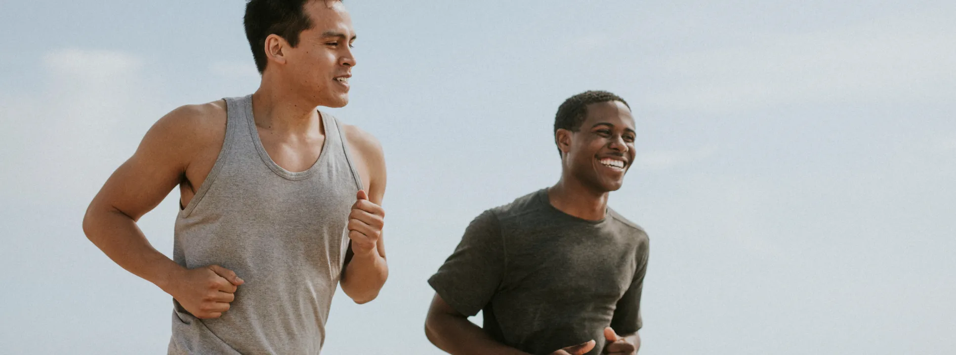 Two men jogging outdoors and smiling, representing increased energy and active lifestyle supported by Shockwave Therapy treatment.