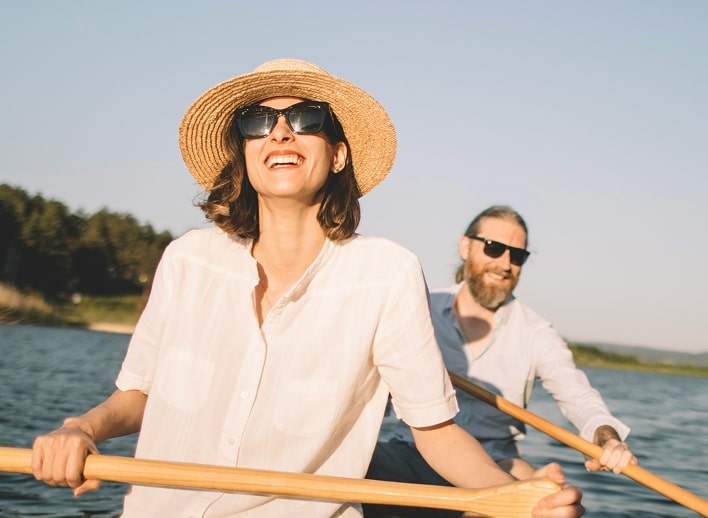 Couple out on a lake in a rowboat, smiling and enjoying the sun.