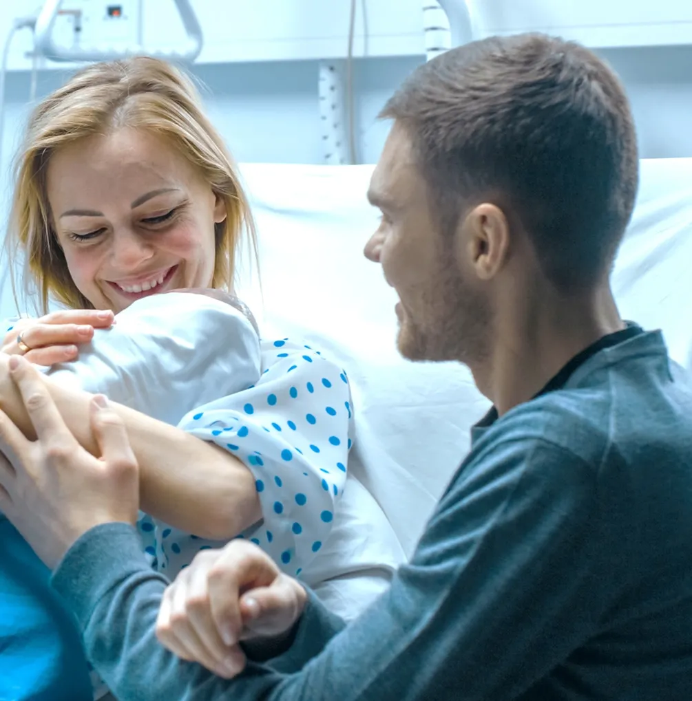 A man holding a baby in a hospital bed.