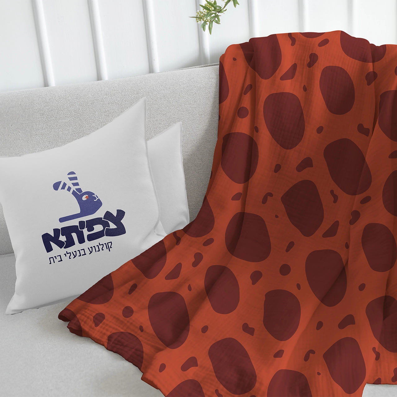 Zafita branded pillow with a brand logo, and a branded blanket with terrazzo pattern