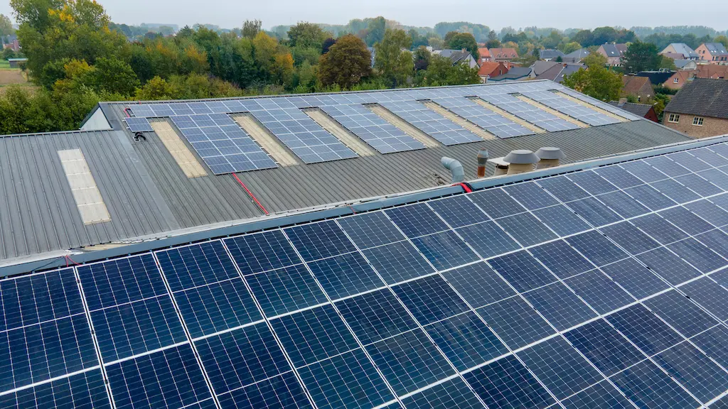 Overzicht van een grootschalig zonnepanelenpark op een industrieel dak in een groene omgeving, professioneel geïnstalleerd door Energy Protect.