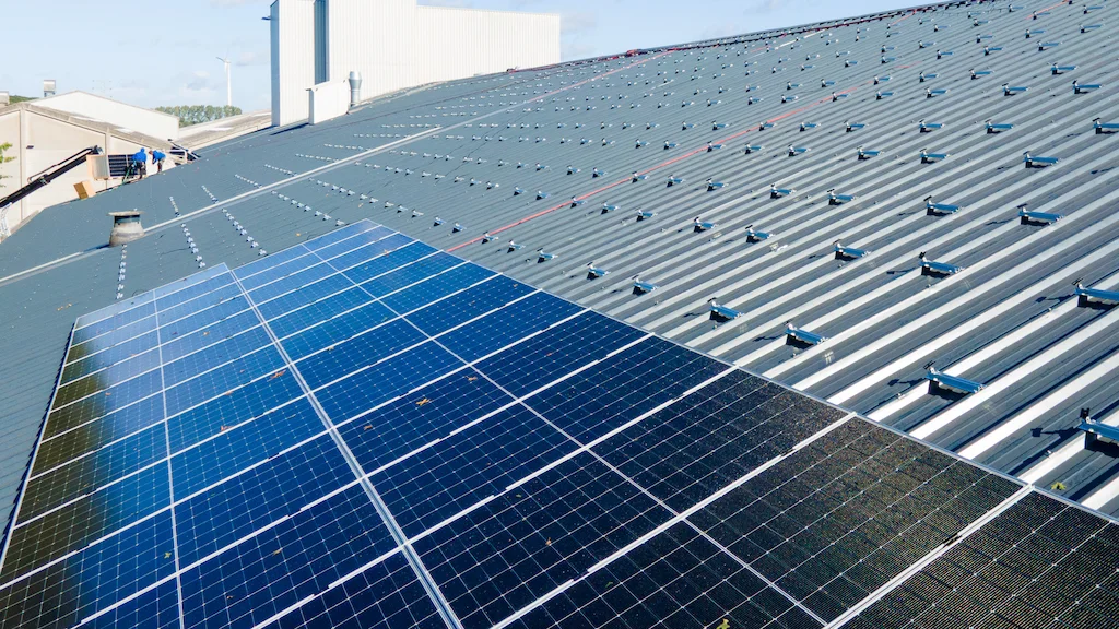 Grootschalige zonnepanelen installatie door Energy Protect op een industrieel trapeziumdak, met zicht op de montagerails voor verdere uitbreiding.