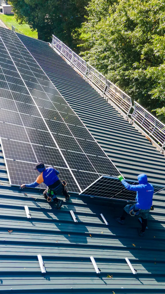 Veilige montage van zonnepanelen door gecertificeerde installateurs van Energy Protect op een metalen bedrijfsdak, voorzien van professionele valbeveiliging.