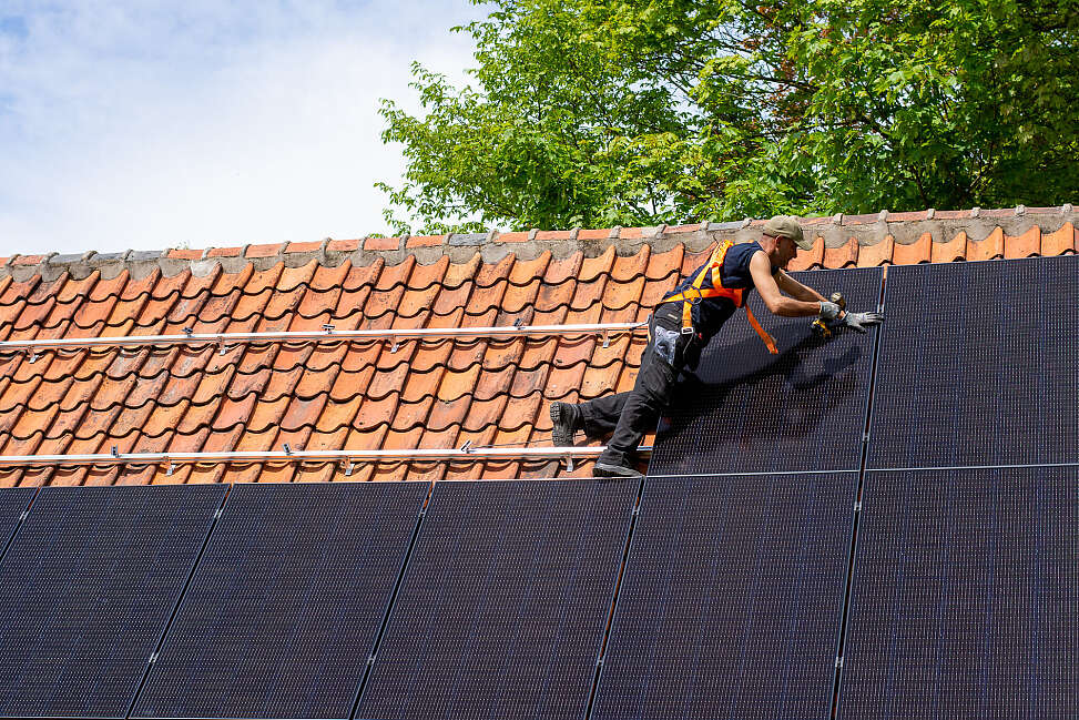 expert installe des panneaux solaires sur le toit