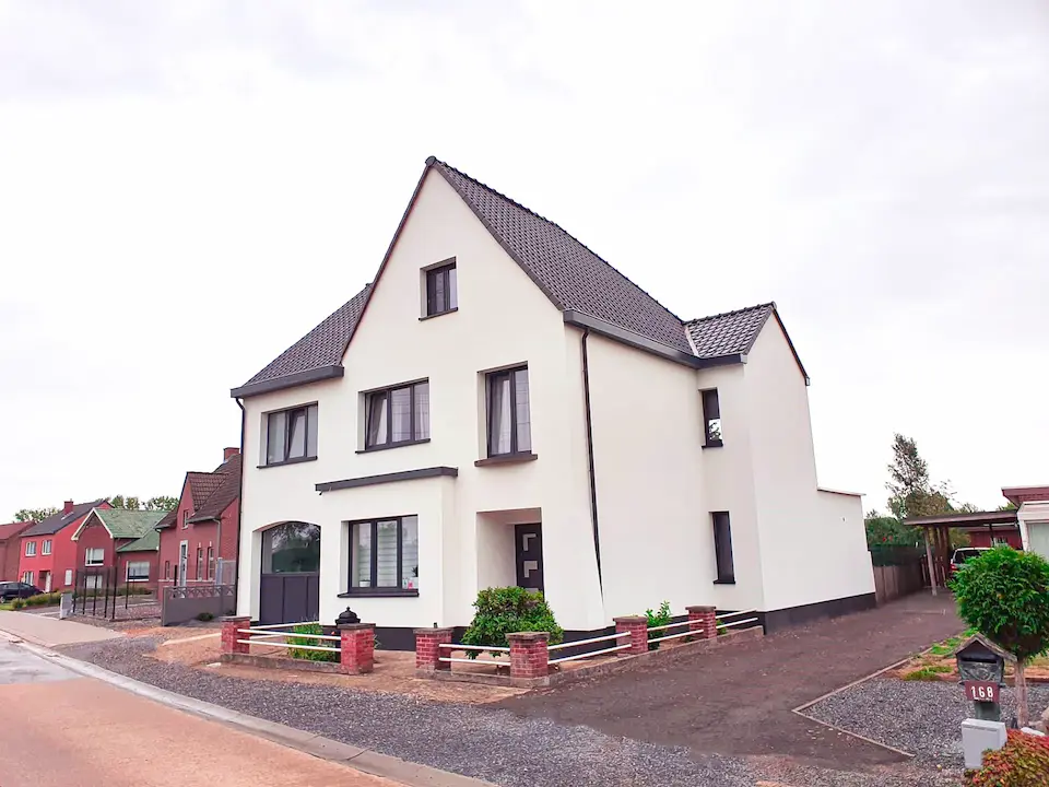 Vrijstaande woning met witte gevel, donkergrijze ramen en een donker pannendak