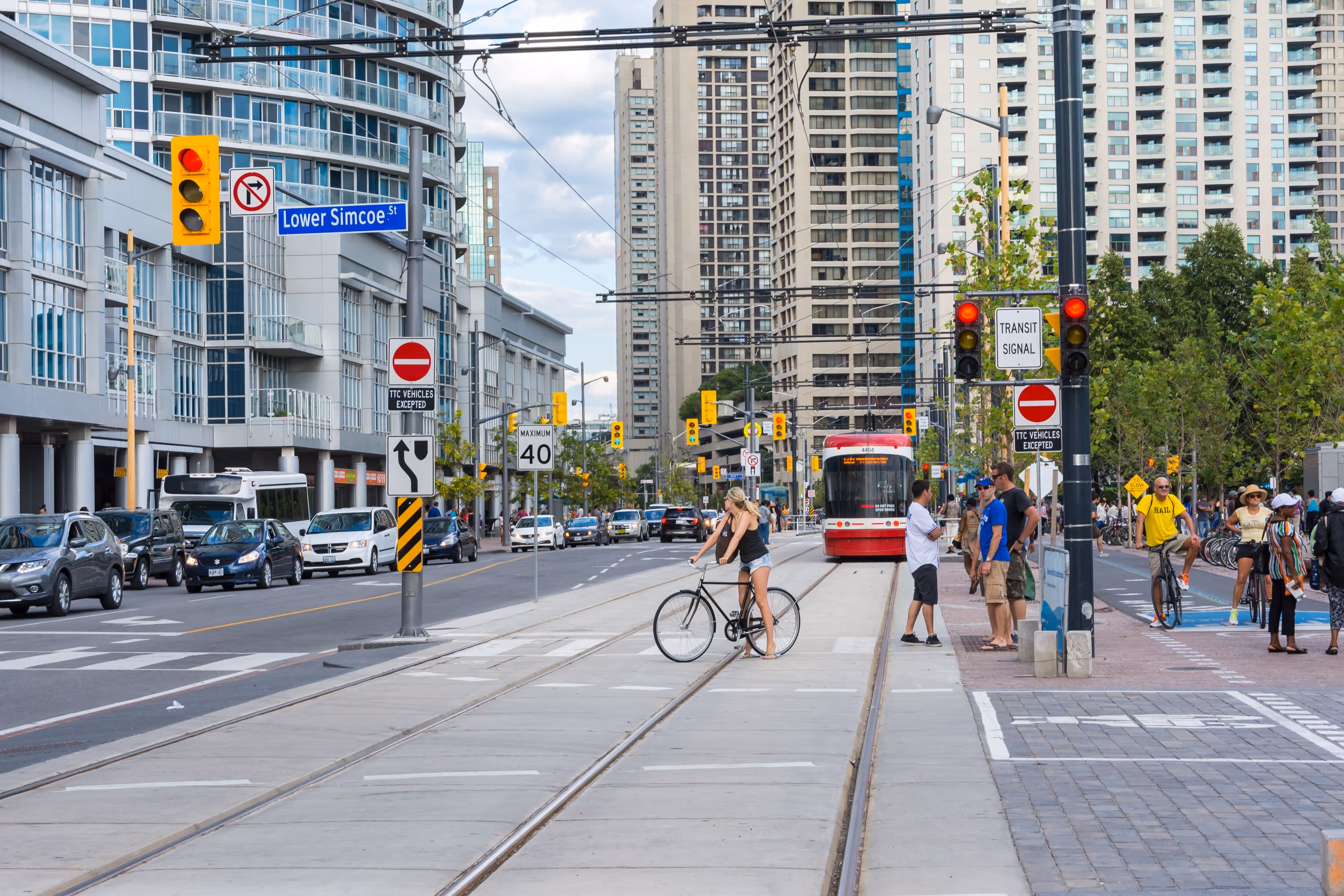 Scène urbaine de Toronto avec tramway, voitures, cyclistes et piétons, illustrant la diversité des modes de transport.