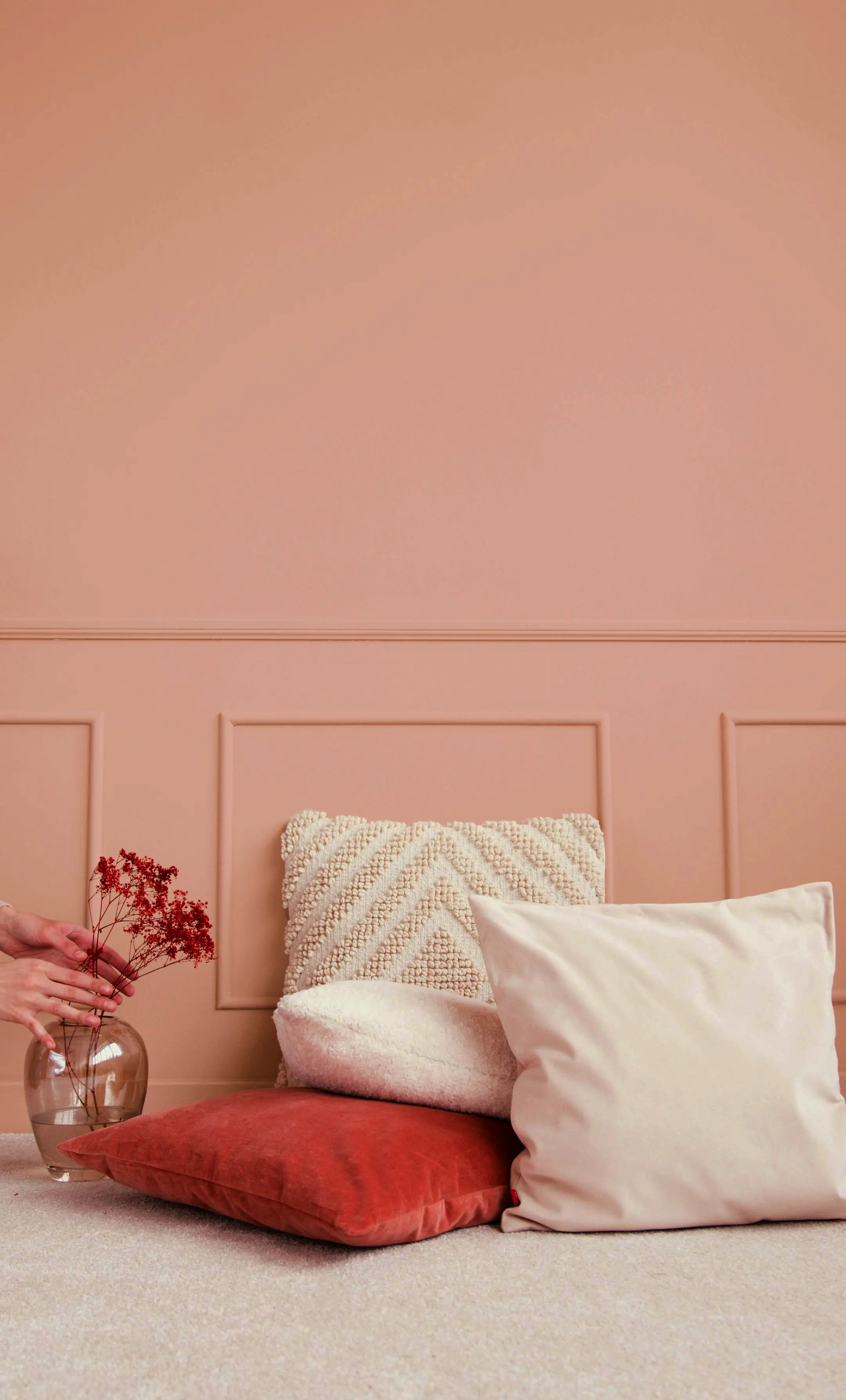 Décoration intérieure douce avec coussins texturés sur mur rosé avec moulures – ambiance élégante en Franche-Comté