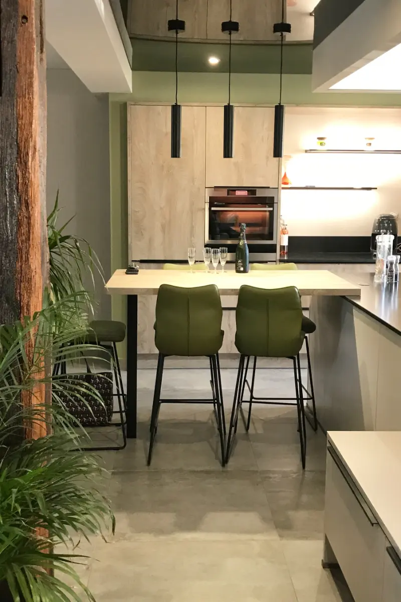 La table et les chaises en velours dans une cuisine rénovée, suspensions métallique noires