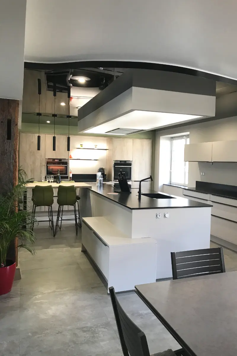 Vue large d'une cuisine complètement rénovée - murs blanc, plafond tendu noir et touches de vert pin