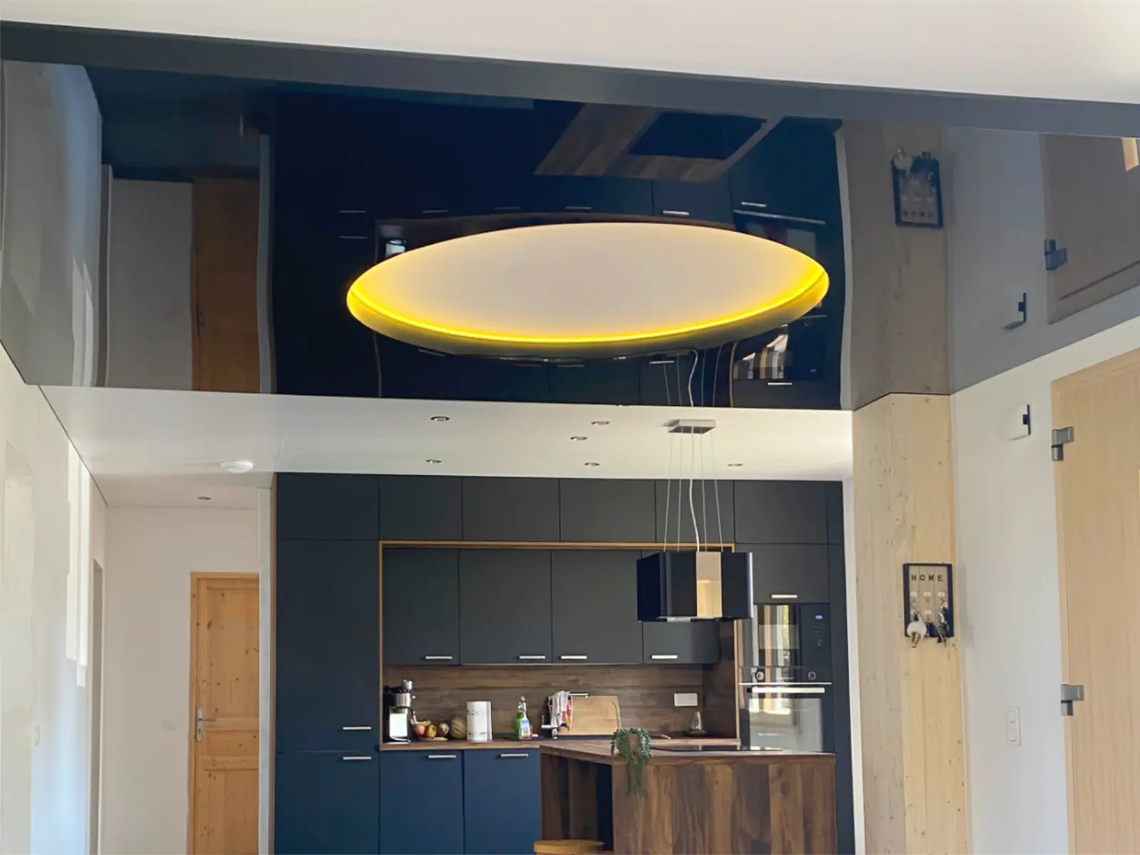 Plafond tendu noir brillant avec des reflets et un grand luminaire rond