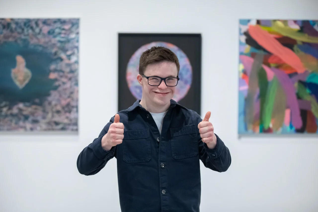 Jodie Cooper Jodie smiling sitting beside her sewing machine in her workspace.