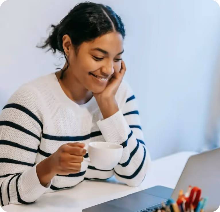 Smiling woman with coffee cup in an online therapy session.