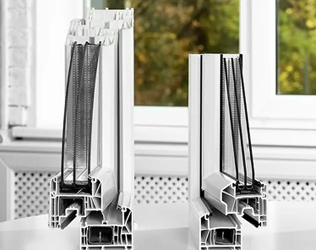 Close-up of two vertical cross-sections of white triple-glazed window frames displayed indoors.