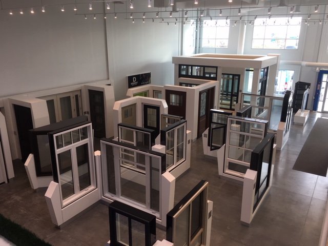 Bright living room with vaulted ceiling, white sectional sofa, glass coffee table, and large windows with ocean view.