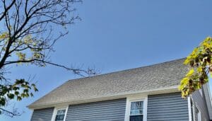 A home with a grey asphalt shingle roof and an expansive blue sky as the backdrop. 