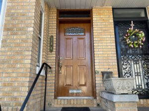 A brick home with a medium brown wood front entry door