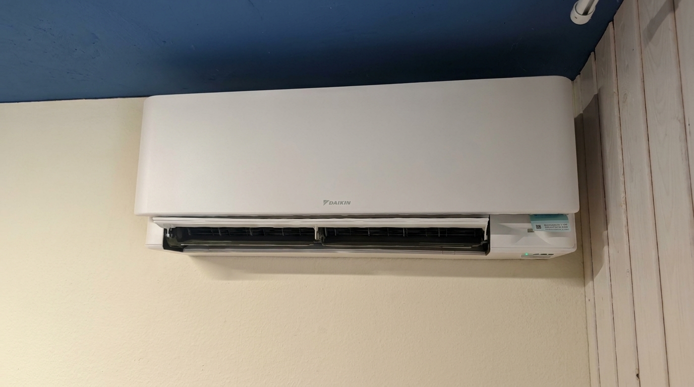 Weisses Daikin-Innengerät an cremefarbener Wand unter blauer Decke